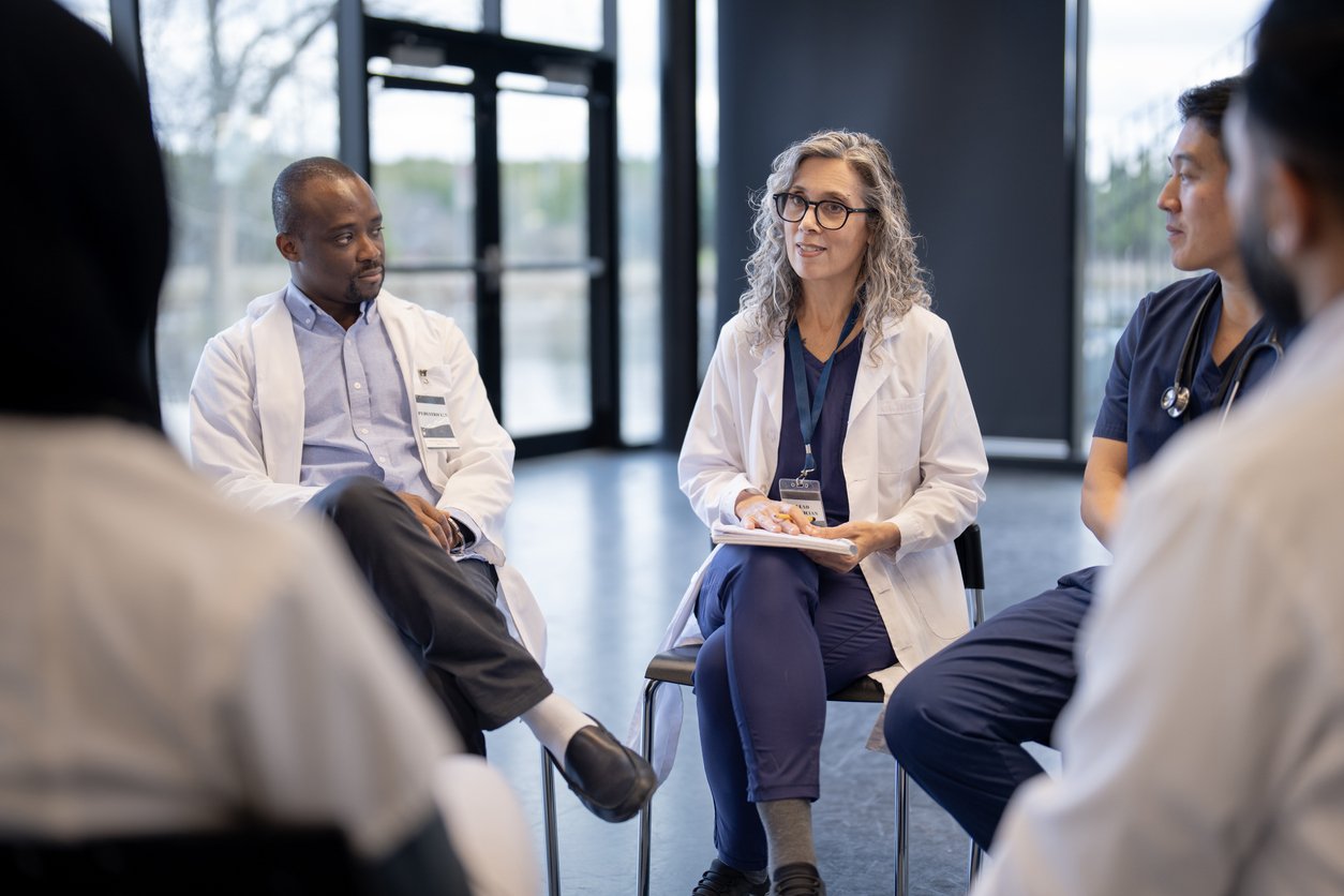 A group of clinicians sitting in a circle for a well-being debriefing