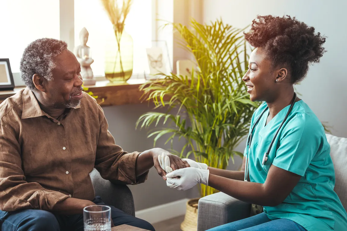 Black male patient sitting with Black clinician in home care setting