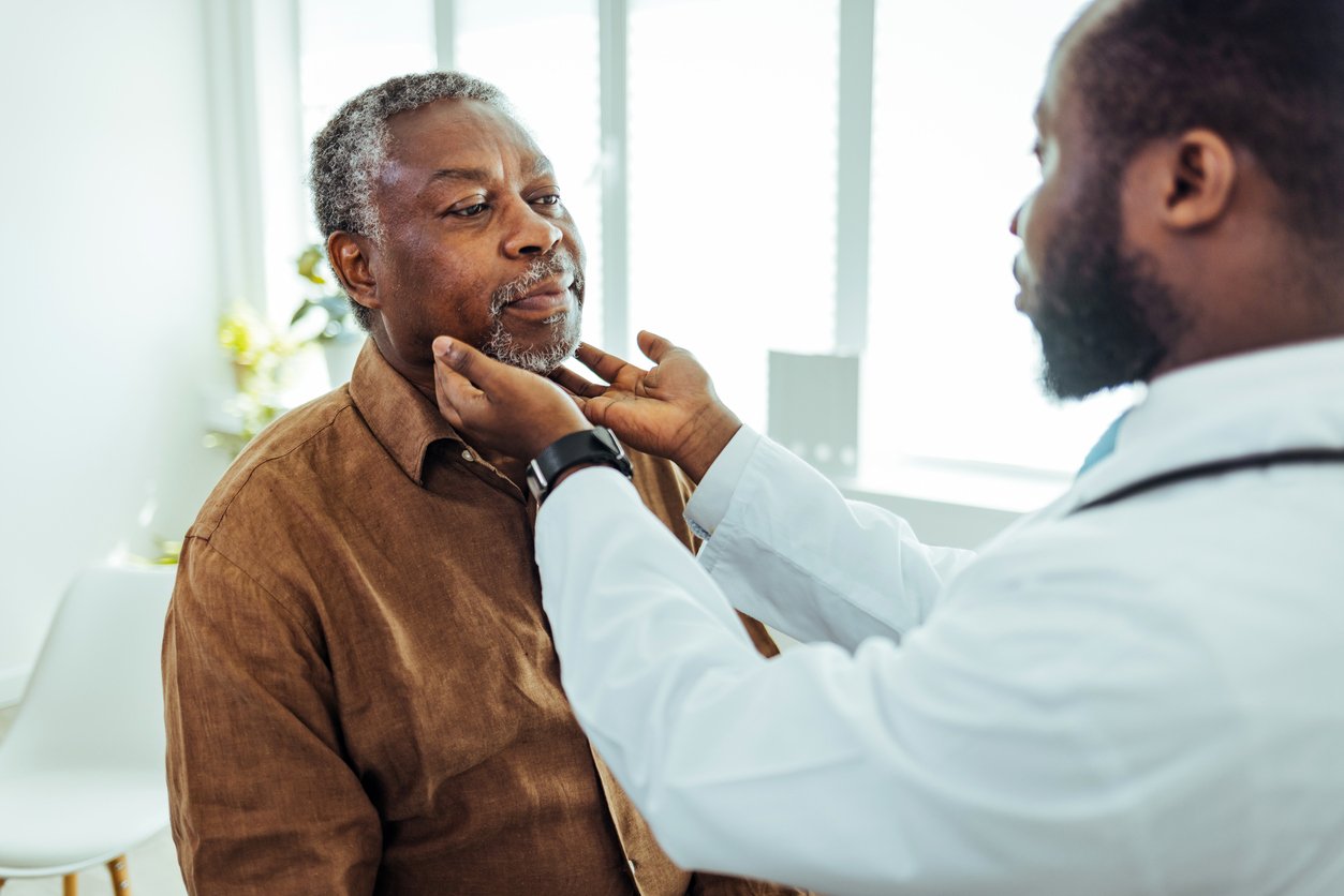 Clinician doing a throat examination on older man