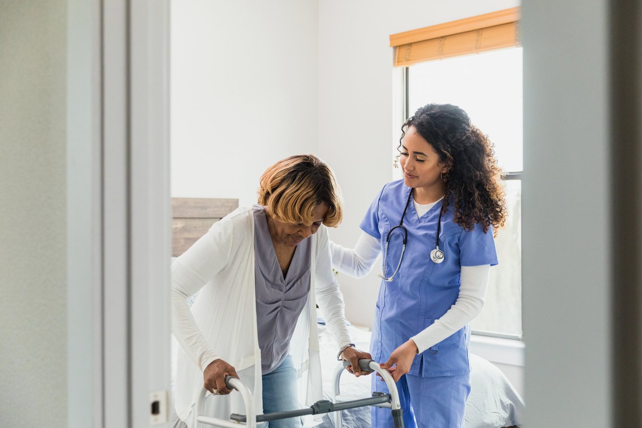 Clinician helping person with serious illness stand with a walker