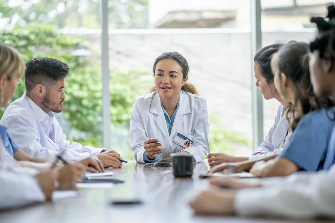Clinicians sitting at a table talking and writing notes
