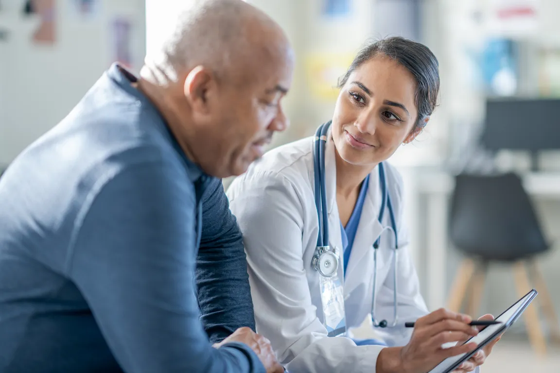 Female clinician provides medical care to senior male patient who is living with HIV