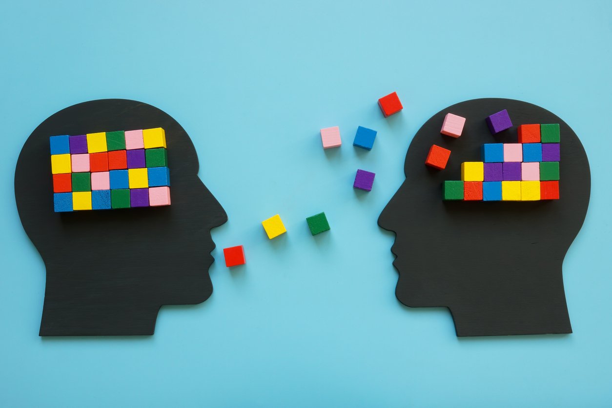 Graphic image representing two people talking and building knowledge via building blocks in head