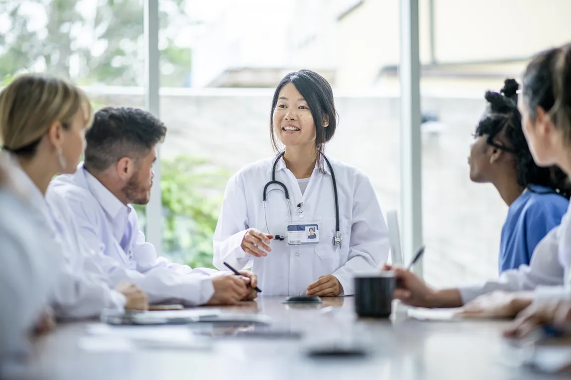 Medical students sit around a table engaged during a lecture