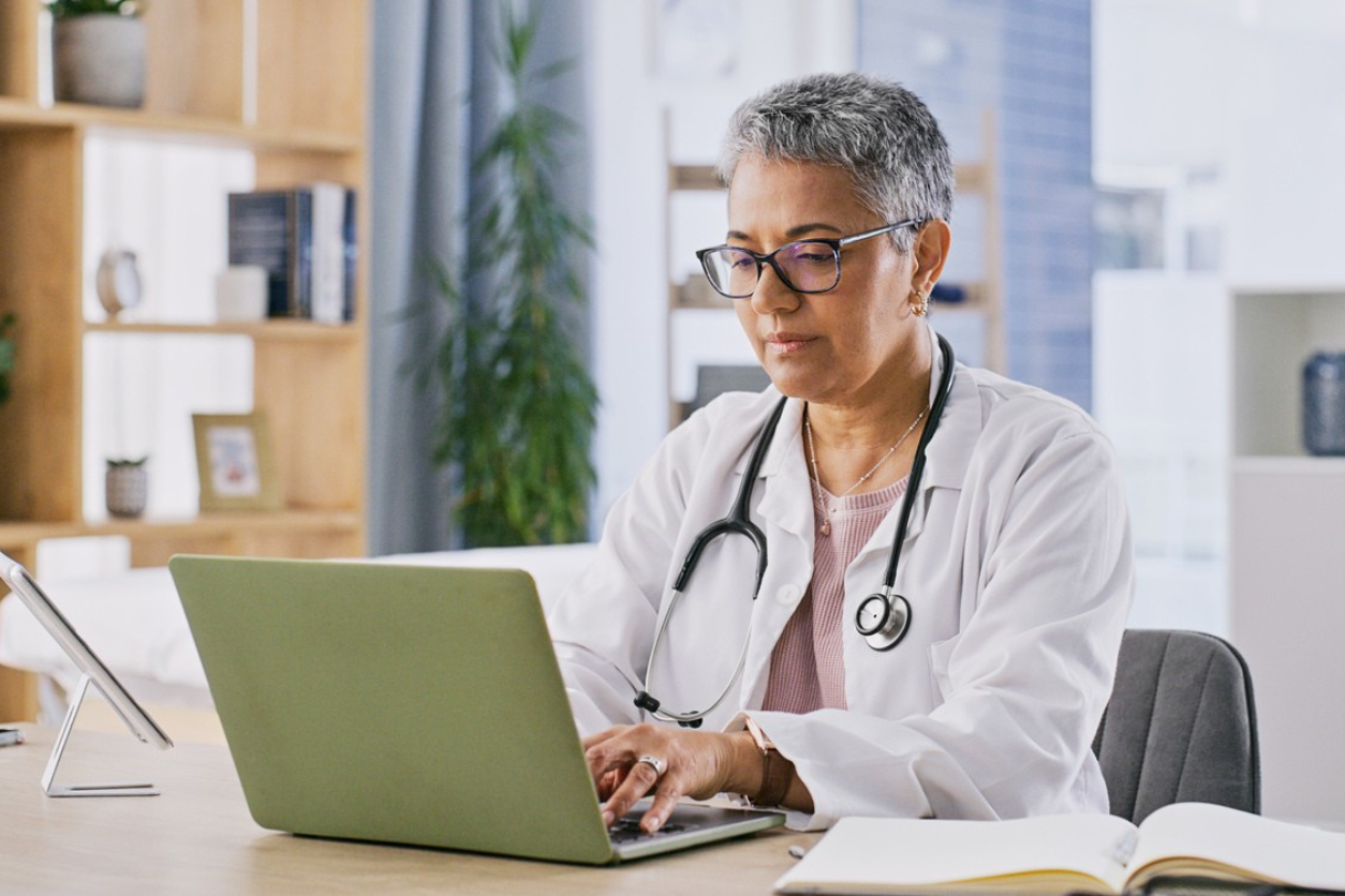 Palliative care doctor using a laptop to update a patient's medical record_1254x836px