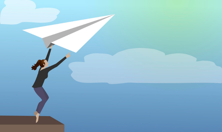 Person grabbing on to a paper airplane flying in the sky_840x500.png