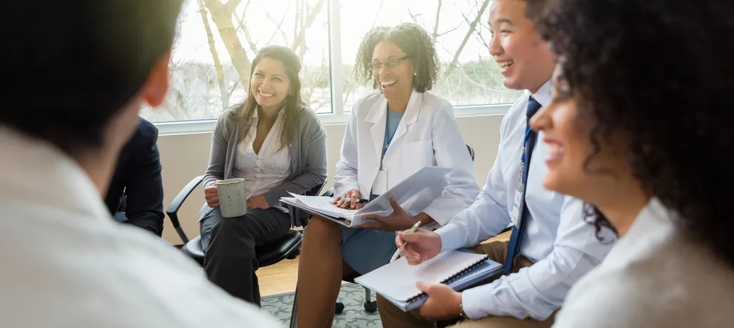 Clinicians sitting in a meeting smiling and talking