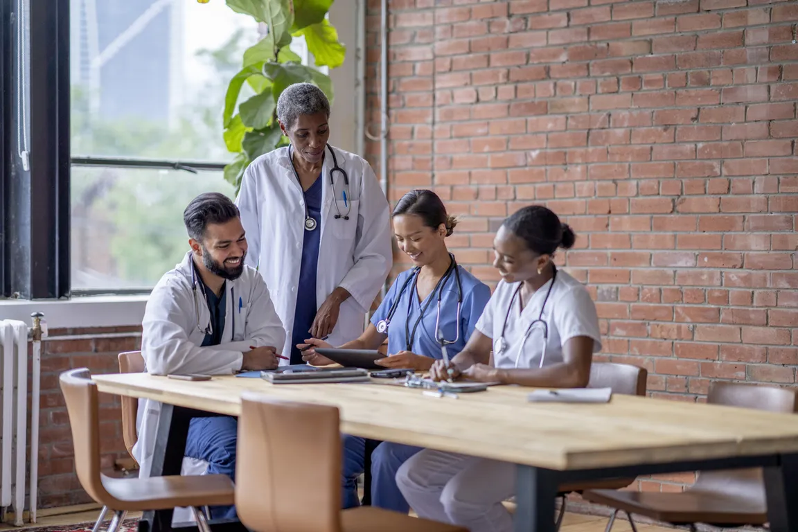 Photograph of four doctors working together at a table - new
