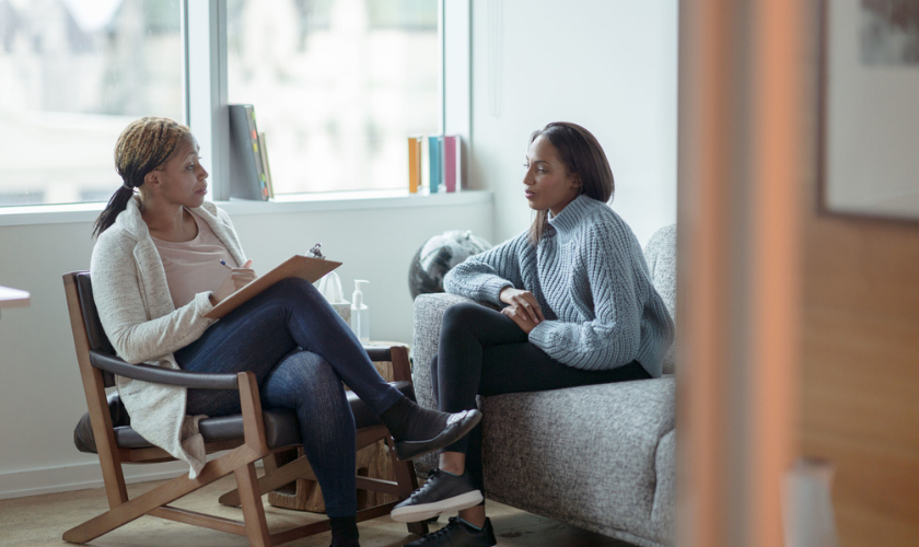 Therapist and client talking through trauma during therapy session_840x500