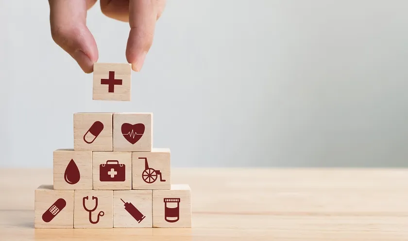 Hand Stacking Wooden Blocks on Table, Health Care Graphics Displayed on Blocks