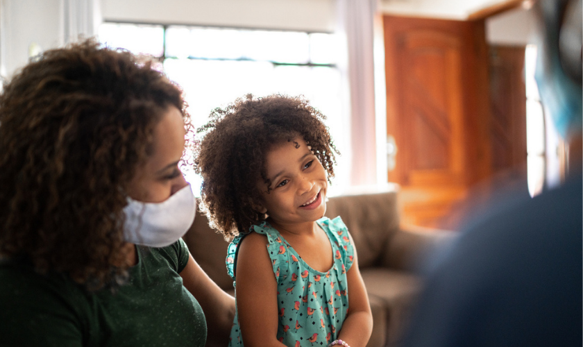 Young girl and mother talking to a clinician during a home visit_840x500