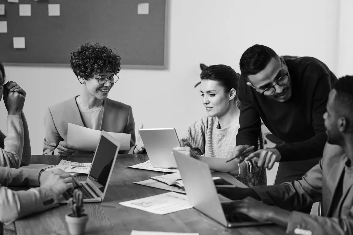 Black and white photo of clinicians sitting around a table on their computers working on their innovative projects